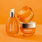 Frasco y tarros Biotherm Aquasource+ de vidrio naranja sobre fondo naranja brillante, con tapas plateadas y gel hidratante visible.