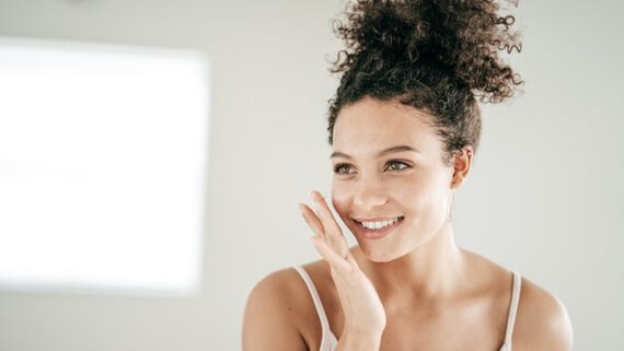 Una mujer sonriendo mientras se cubre la cara con la mano.